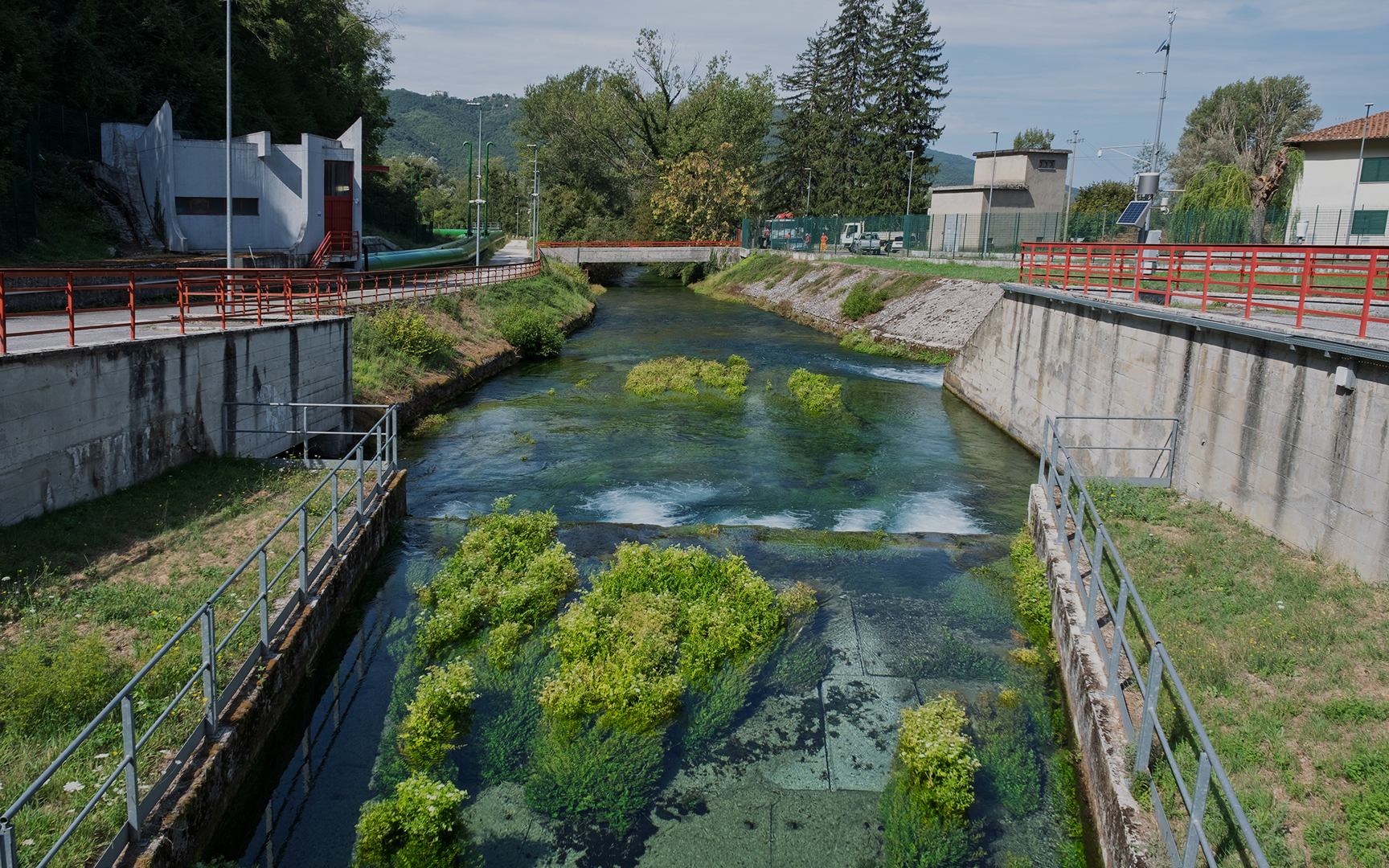 Corso d’acqua affiancato da strutture tecniche per il monitoraggio e la gestione idrica