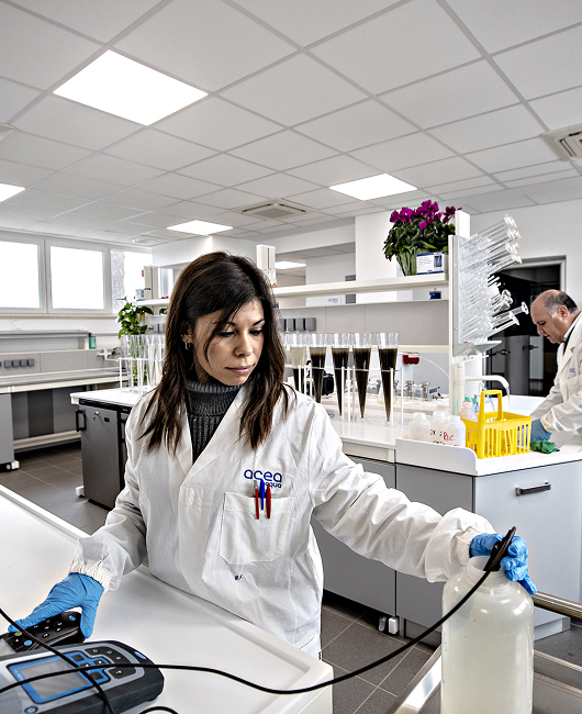 Ricercatrice di Acea Ato 5 in camice bianco mentre analizza un campione d’acqua in laboratorio